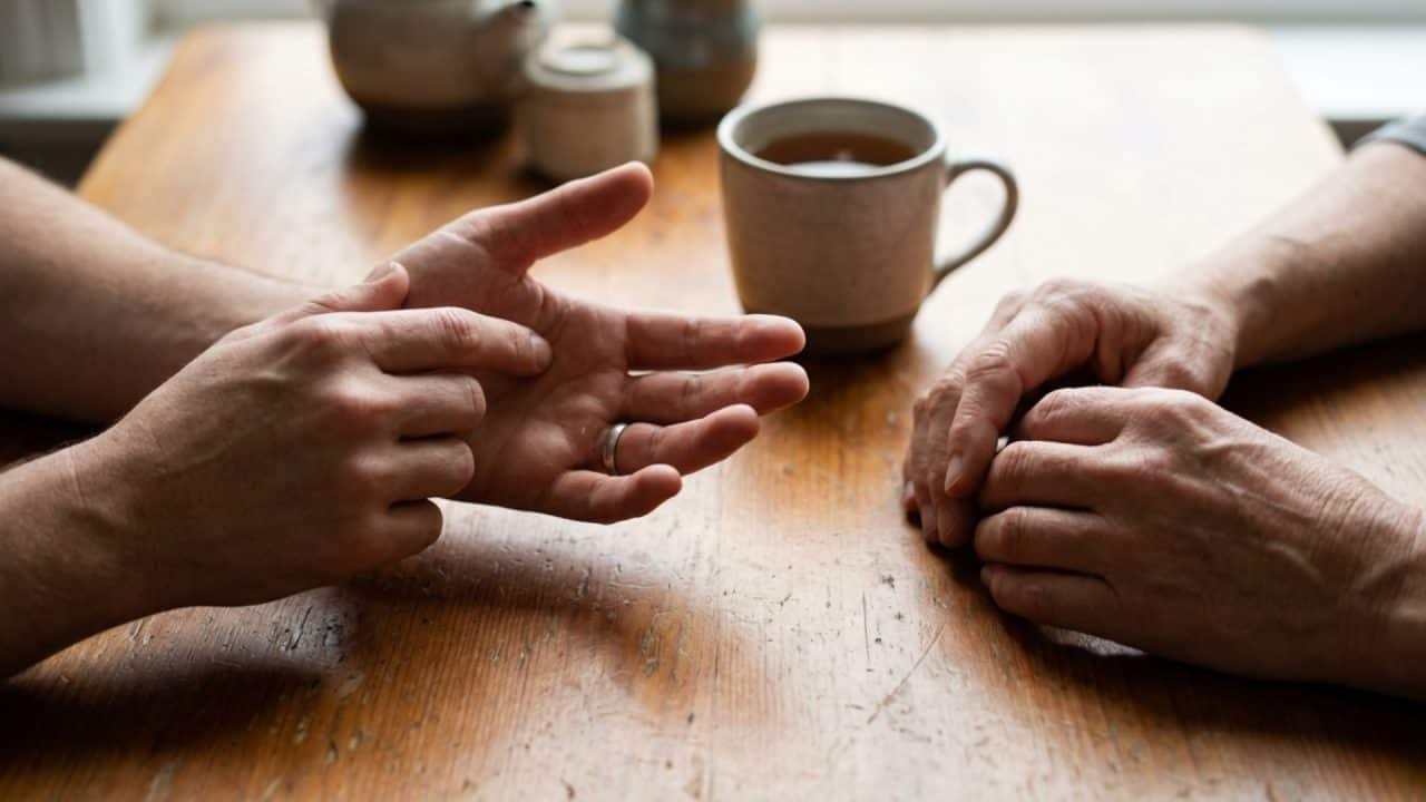 Close-up van handen tijdens een coachinggesprek over het loslaten van emotionele blokkades