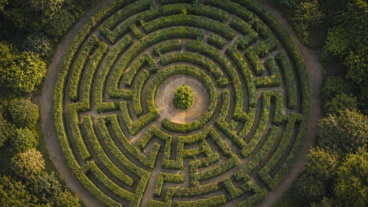 Doolhof van groene heggen van bovenaf als symbool voor zoeken, patronen en vastlopen bij het kiezen van de juiste coaching
