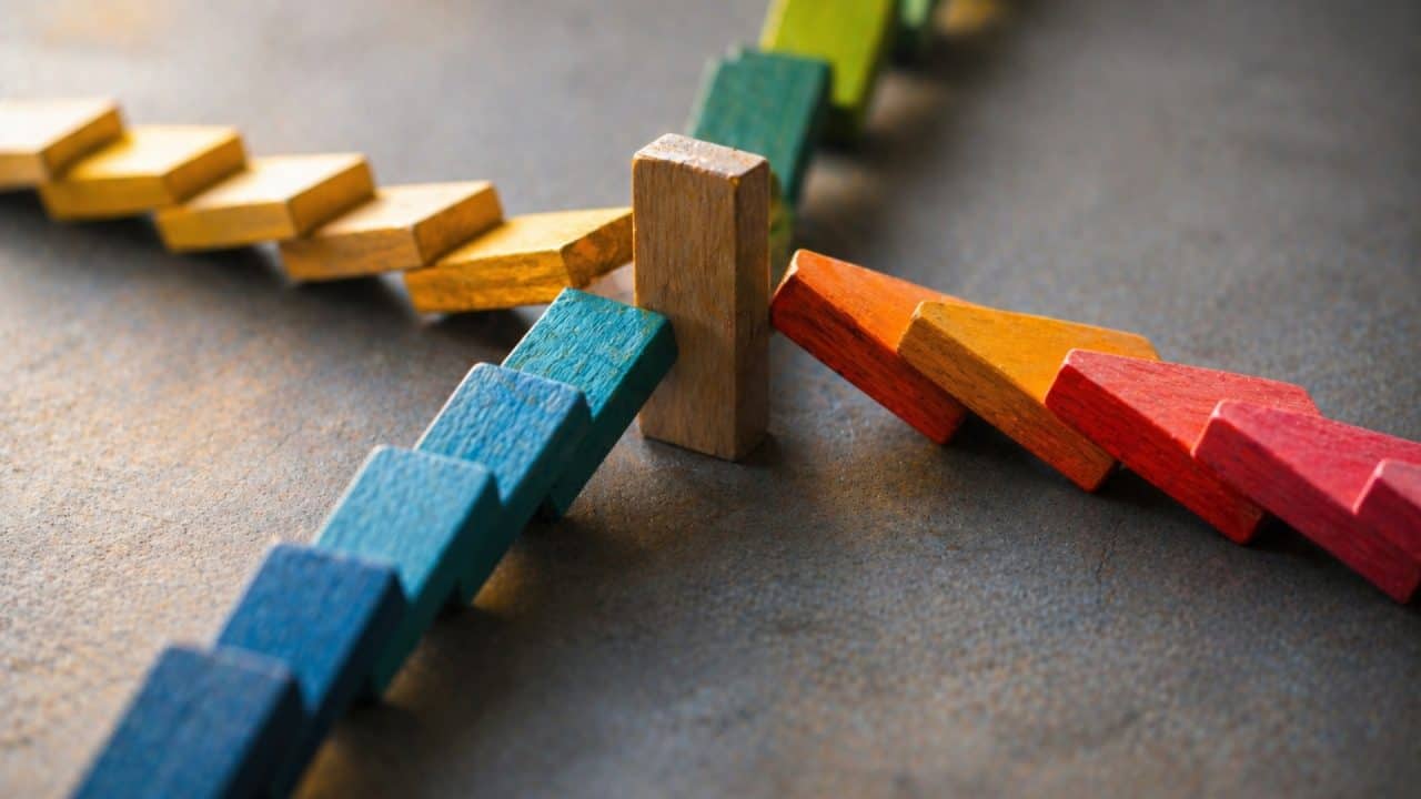 Domino-opstelling waarbij één blok meerdere richtingen tegelijk ondersteunt als symbool voor oververantwoordelijkheid